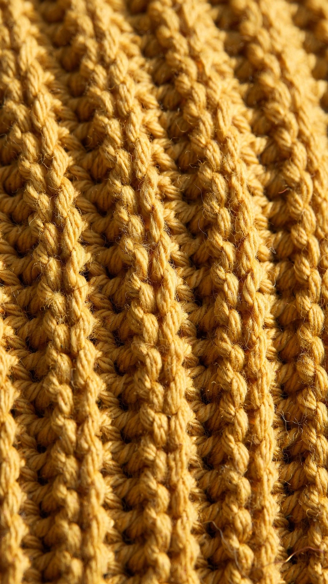 Macro close up of ribbed crochet texture made with half double crochet in the back loop only in mustard yarn